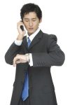 An asian businessman checks the time whist taking on the telephone