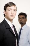 A smart caucasian businessman in a suit (in focus) with another businessman behind (out of focus)